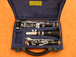Photo de clarinette en si bémol démontée, dans son étui. De gauche img droite et de haut en bas : le baril, le corps du bas, le bec, le pavillon, et le corps du haut.